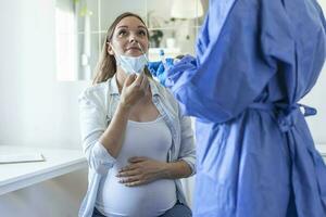 Healthcare worker with protective equipment performs coronavirus swab on pregnant woman.Nose swab for Covid-19. photo