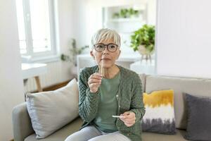 Mature woman taking a Self-swabbing home tests for COVID-19 at home with Antigen kit. Introducing nasal stick to check the infection of Coronavirus. Quarantine, pandemic. photo