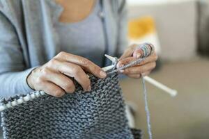 Close up view grandmother hands holding needles make repetitive motion knitting sitting on couch creating something with her arms. Hand knitting improve brain function, older generation hobby concept photo
