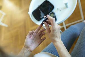 Test Blood Glucose For Diabetes in Pregnant Woman With Glucometer. One red drop of blood on the finger ready to measure sugar level. Close up of male finger with blood drop and test stripe photo