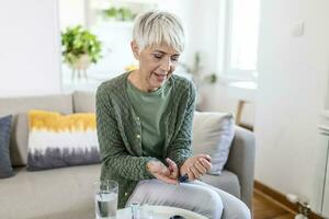 Mature woman with glucometer checking blood sugar level at home. Diabetes, health care concept photo