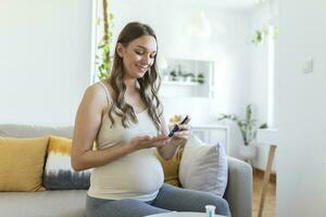 Pregnant Woman testing for high blood sugar. Woman holding device for measuring blood sugar. Pregnant Woman doing blood sugar test. checking blood sugar level by glucometer and test stripe at home photo