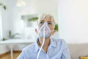 enfermo mayor mujer haciendo inhalación, medicina es el mejor medicamento. enfermo mayor mujer vistiendo un oxígeno máscara y pasando tratamiento para COVID-19. mayor mujer con un inhalador foto