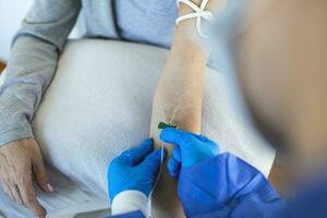 Senior woman sitting in the hospital chair while receiving IV infusion in medicine center photo