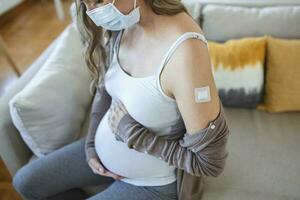 Pregnant woman with adhesive bandage on her arm after Corona virus vaccine. First aid. Medical, pharmacy and healthcare concept. photo