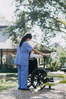 young asian physical therapist working with senior woman on walking with a walker photo