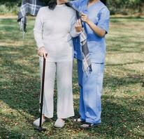 young asian physical therapist working with senior woman on walking with a walker photo