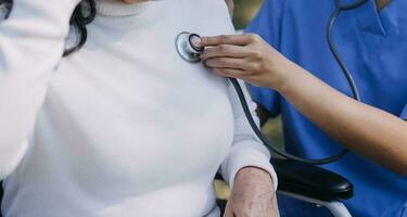 young asian physical therapist working with senior woman on walking with a walker photo