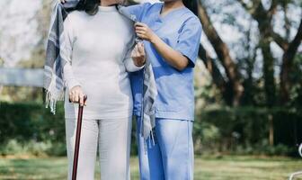 young asian physical therapist working with senior woman on walking with a walker photo