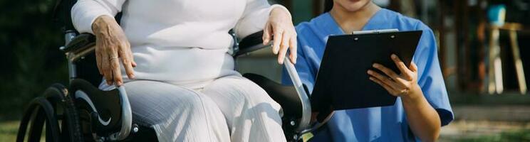 young asian physical therapist working with senior woman on walking with a walker photo