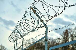 Barbed wire on fence restrict access to the restricted area. photo