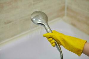 Female hand holds shower head with pouring water, copy space photo