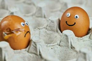 Funny egg and sad cracked egg in paper egg tray photo