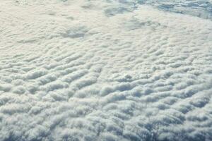 Breathtaking over clouds view from aircraft window, thick white blue clouds looks like soft foam photo
