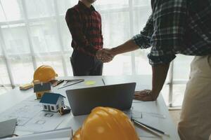 Happy workers at construction site, young civil engineer manager and architects handshaking at construction site and looking to next construction phase , cooperation teamwork concept. photo