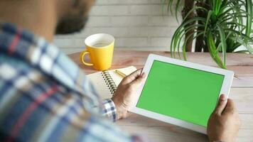 uomo utilizzando tavoletta con verde schermo su il tavolo video