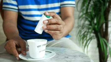 en man är sätta artificiell sötningsmedel in i en kopp av te video