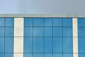 Blue glass office building wall with blue sky background photo