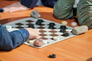 Outdoor checkers tournament on paper checkerboard on table, close up players hands photo