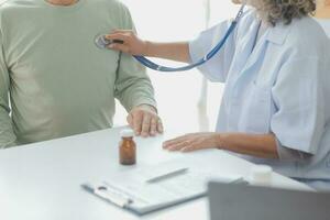 Mature Asian male doctor talking with his patient, explaining the procedure to old lady. photo