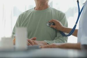 Mature Asian male doctor talking with his patient, explaining the procedure to old lady. photo