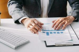 Close up Business woman using calculator and laptop for do math finance on wooden desk, tax, accounting, statistics and analytical research concept photo