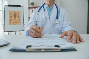 Doctor giving hope. Close up shot of young female physician leaning forward to smiling elderly lady patient holding her hand in palms. Woman caretaker in white coat supporting encouraging old person photo