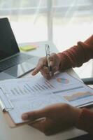 Asian Businesswoman Using laptop computer and working at office with calculator document on desk, doing planning analyzing the financial report, business plan investment, finance analysis concept. photo