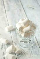 Glass bowl of marshmallows on the wooden background photo