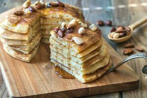 Stack of pancakes with maple syrup and nuts photo