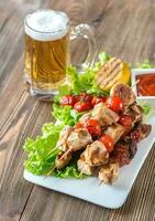 Grilled chicken skewers with mug of beer photo