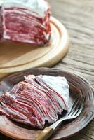 Portion of red velvet crepe cake on the wooden table photo