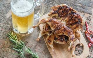 Grilled quails with glass of beer photo