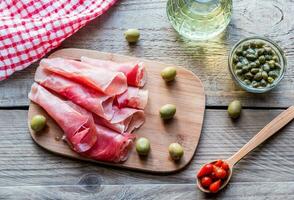 Jamon with capers and olives on the wooden board photo