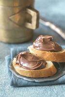 Slices of baguette with chocolate cream on the saucer photo