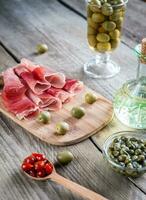 Jamon with capers and olives on the wooden board photo