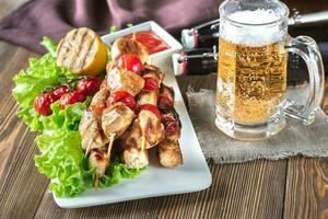 Grilled chicken skewers with mug of beer photo