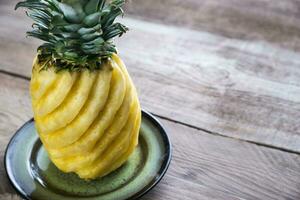 Pineapple on the plate on the wooden background photo