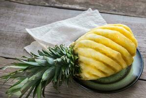 Pineapple on the plate on the wooden background photo