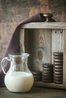 Chocolate cookies with creamy filling with jug of milk photo