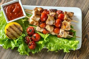 brochetas de pollo a la parrilla en el plato blanco foto