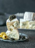 White and blue mold cheese with black caviar close-up photo