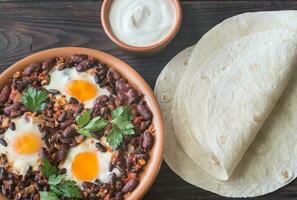 Bowl of chipotle bean chili with baked eggs photo