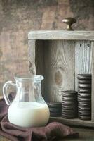Chocolate cookies with creamy filling with jug of milk photo