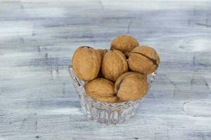 Walnuts in a shell on a painted background in a crystal vase. Healthy nuts. photo