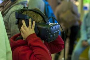 Close-up of a boy wearing virtual reality glasses. He is amazed at what he sees. photo