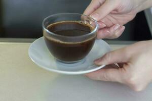 Women's hands hold a cup of coffee over the table. Breakfast with coffee. Make coffee in a turk. photo