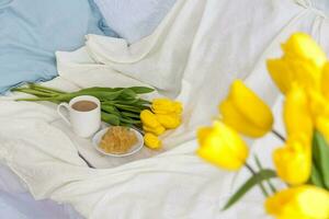 un ramo de flores de Fresco amarillo tulipanes y desayuno con café y hecho en casa mermelada. desayuno en cama. primavera flores el concepto de primavera y día festivo, marzo 8, internacional De las mujeres día, foto