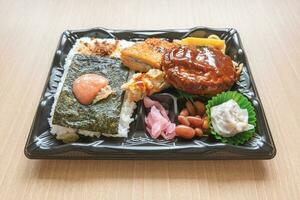 japonés bento conjunto almuerzo caja de hamburguesa bife, algas marinas en arroz, frito pescado y japonés arrollado tortilla foto