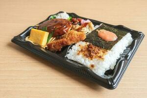 Japanese bento set lunch box of hamburger steak, seaweed on rice, fried fish and Japanese rolled omelet photo